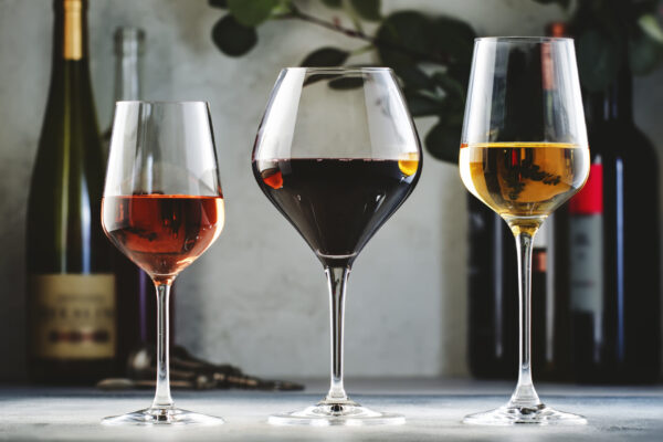 Wines assortment. Red, white, rose wine in wineglasses and bottles on gray background.